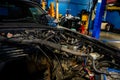 Open car hood without engine being repaired in a car mechanic`s garage. Showing wires and piping parts of a car`s engineering