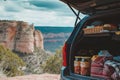 open car trunk filled with picnic items, cliff backdrop