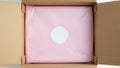 Open cardboard box with pink fabric and white circle Royalty Free Stock Photo