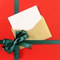 Open Christmas or birthday card with green gift ribbon bow on plain red background paper, copy space, vertical Royalty Free Stock Photo