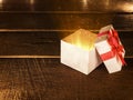 Open Christmas white gift box with ray of magic light on wood desk