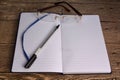 Open a clean Notepad, pen, glasses. Pen, glasses and notebook.