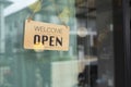 Open and closed flip sign in front of coffee shop and restaurant glass door. Wooden sign with wording of place`s status. Say Royalty Free Stock Photo