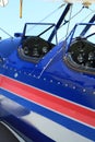 Open cockpit red white and blue aircraft airplane at airport close up featuring pilots and passenger or copilots seats instruments