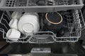 Open compartments of different tiers of the dishwasher with plates and mugs, after cleaning, top view