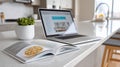 Open cookbook on a kitchen counter beside a laptop displaying a website