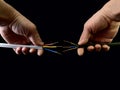 Open copper wires in a male hand. Electro wiring in hands, on a black background. Electrician