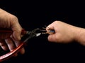 Open copper wires in a male hand. Electro wiring in hands, on a black background. Electrician