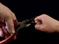 Open copper wires in a male hand. Electro wiring in hands, on a black background. Electrician