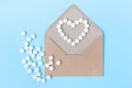 Open craft envelope on a light blue background.White pills in the form of a heart.Letter, message, news.