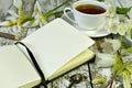 Open diary with copy space pages, cup of tea and flowers on wooden table Royalty Free Stock Photo