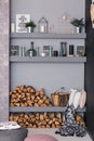 Open dining room interior with firewood, shelves on the grey wall and wooden log wall decoration for warm cozy Royalty Free Stock Photo