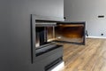 Open, dirty corner pane in a modern fireplace with a closed combustion chamber standing in the living room, painted black. Royalty Free Stock Photo