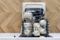 Open dishwasher with ceramic utensils as part kitchen interior design Royalty Free Stock Photo