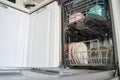 Open dishwasher with clean dishes and cups in modern kitchen setting Royalty Free Stock Photo