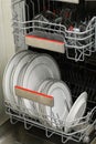 Open dishwasher with clean dishes in a white kitchen Royalty Free Stock Photo