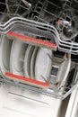 Open dishwasher with clean dishes in a white kitchen Royalty Free Stock Photo