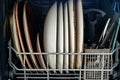 Open dishwasher with clean utensils in white kitchen