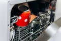 Open dishwasher close up clogged with clean washed dishes. dry cutlery closeup. spoons forks. mugs, plates. household appliances Royalty Free Stock Photo