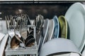 Open dishwasher close up clogged with clean washed dishes. dry cutlery closeup. spoons forks. mugs, plates. household appliances Royalty Free Stock Photo