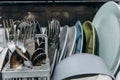 Open dishwasher close up clogged with clean washed dishes. dry cutlery closeup. spoons forks. mugs, plates. household appliances Royalty Free Stock Photo