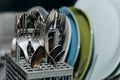 Open dishwasher close up clogged with clean washed dishes. dry cutlery closeup. spoons forks. mugs, plates. household appliances Royalty Free Stock Photo