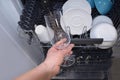 An open dishwasher with dishes, a man pulls out a clean glass by hand. Image Royalty Free Stock Photo