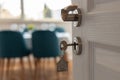 Open door to a new home. Door handle with key and home shaped keychain. Mortgage, investment, real estate, property and new home