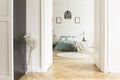 Open door to white bedroom interior with herringbone parquet, ki