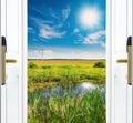 Open door with a view of green meadow illuminated by bright sunshine Royalty Free Stock Photo
