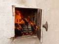 Open door white rustic stoves, burning wood and fire