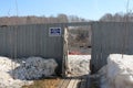 An open door in the wooden fence with a sign place for dogs of the city outskirts the village of Koltsovo in the winter