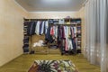 Open dressing closet wardrobe full of different male and female colorful clothes and accessories on hangers and shelf. Modern