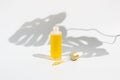 Open glass dropper bottle of yellow serum or essential oil and eyedropper isolated on white. Organic skin care cosmetics