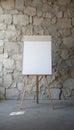 Open easel with blank white board against rustic stone wall. Royalty Free Stock Photo