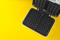 Open electric waffle maker on yellow background, top view. Space for text Royalty Free Stock Photo