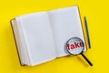 Open empty notebook with magnifier for fake news on yellow background in style of Zine Royalty Free Stock Photo