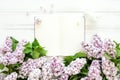 Open empty notebook surrounded with lilac flowers on white wooden background. Flat lay, top view, copy space Royalty Free Stock Photo