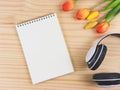 open empty page notebook, white headphones and red yellow tulip flowers on wooden table background with copy space. Love song, Royalty Free Stock Photo