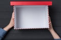 Open empty red box in children`s hands on black background. Top view Royalty Free Stock Photo