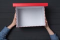 Open empty red box in children`s hands on black background. Top view Royalty Free Stock Photo