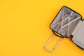 Open empty suitcase on yellow background, top view. Space for text Royalty Free Stock Photo