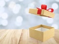 open empty luxury gold gift box with red ribbon bow on wooden table top with defocused blue and white christmas lights bokeh Royalty Free Stock Photo