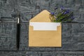 An open envelope with a white sheet of paper, a fountain pen and flowers on a wooden background. Flat lay Royalty Free Stock Photo