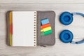 Open exercise book on bag-pencil case with color felt pens and marker, headphones on gray wooden boards Royalty Free Stock Photo