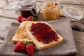 Open face peanut butter and jelly sandwich on napkin with jars and strawberries at table Royalty Free Stock Photo