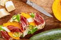 Open faced sandwich with iberico ham, parmesan and goat cheese, zucchini, pumpkin on sourdough bread. on cutting board. top view Royalty Free Stock Photo