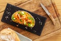 Open faced sandwich with smoked salmon, avocado, apple, zucchini, pumpkin, basil and chives on toasted sourdough bread. on wood.