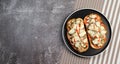 Open faced sandwiches with chicken, pickles and cheese on a round plate on a dark background