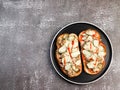 Open faced sandwiches with chicken, pickles and cheese on a round plate on a dark background